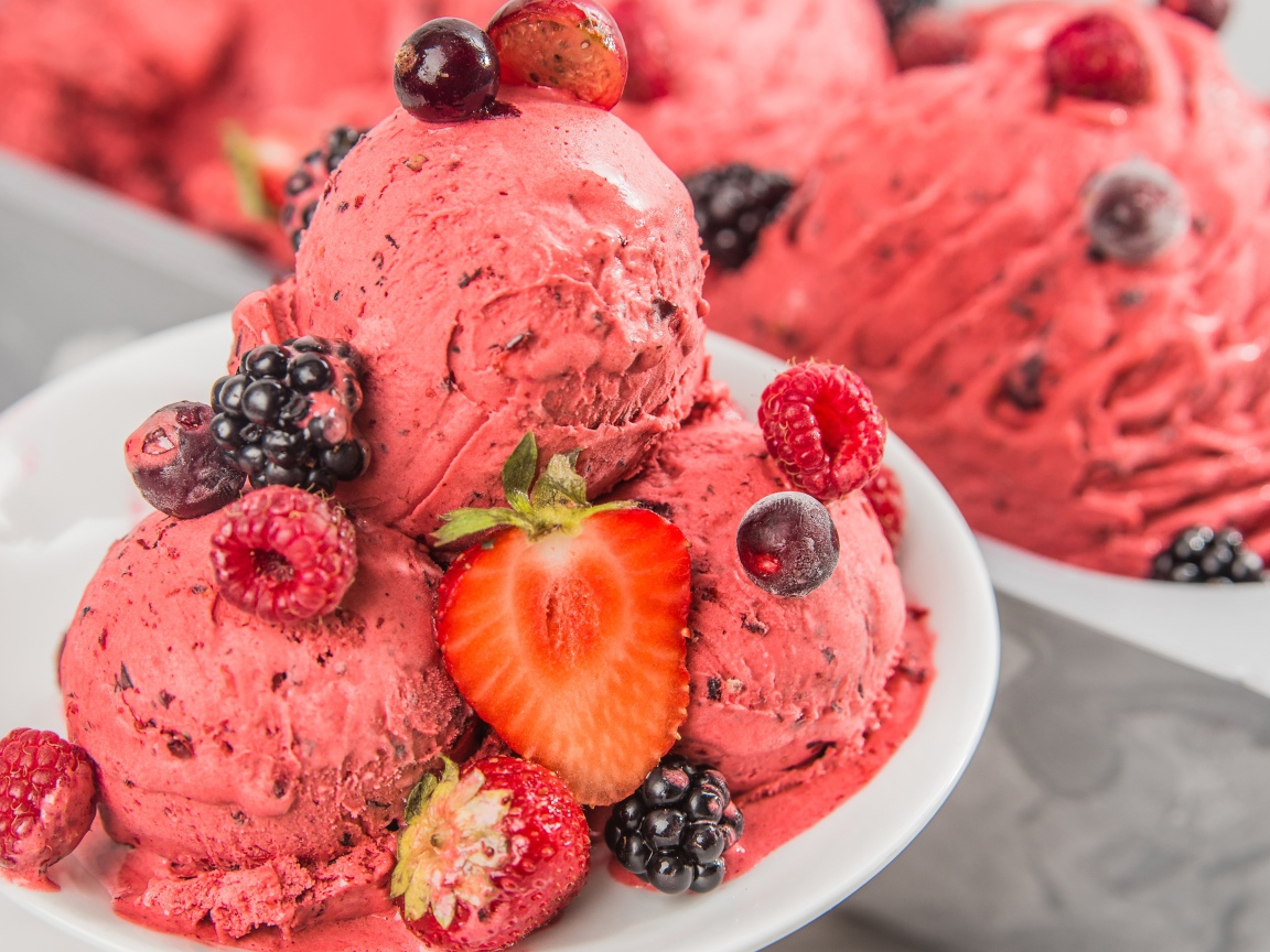 Шарики фруктового мороженого на тарелке с ягодами 