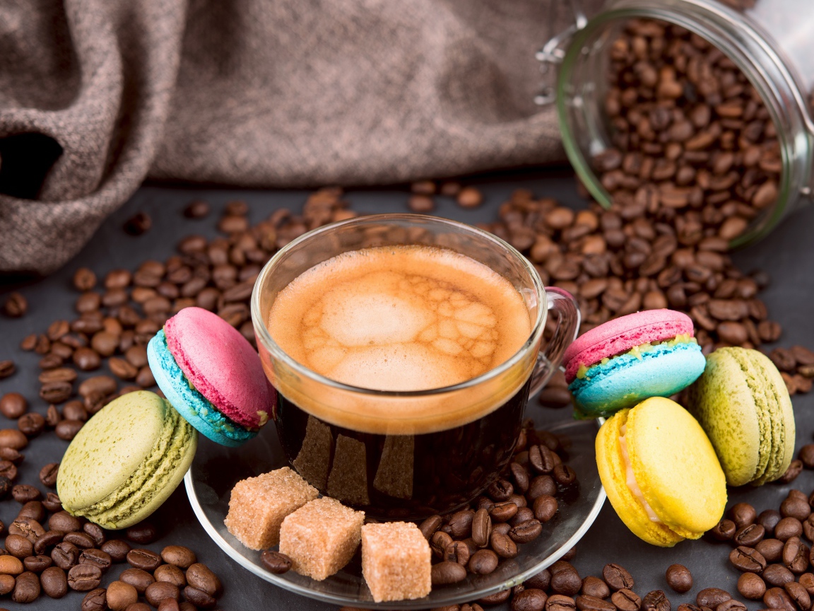 Чашка кофе с кофейными зернами, кубиками сахара и десертом макарон