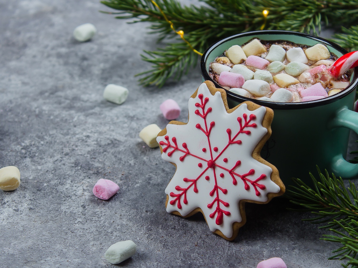 Чашка горячего напитка с кусочками маршмеллоу на столе с печеньем 