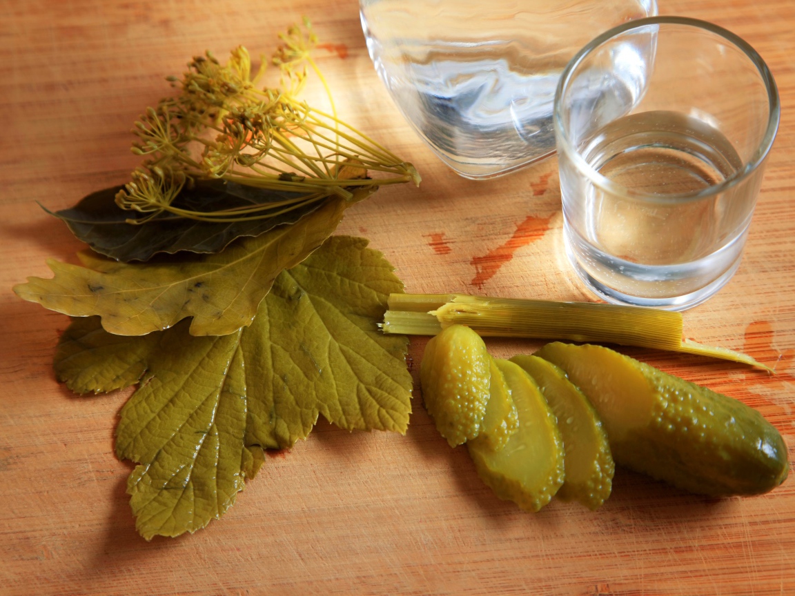 Рюмка водки на столе с соленым огурцом