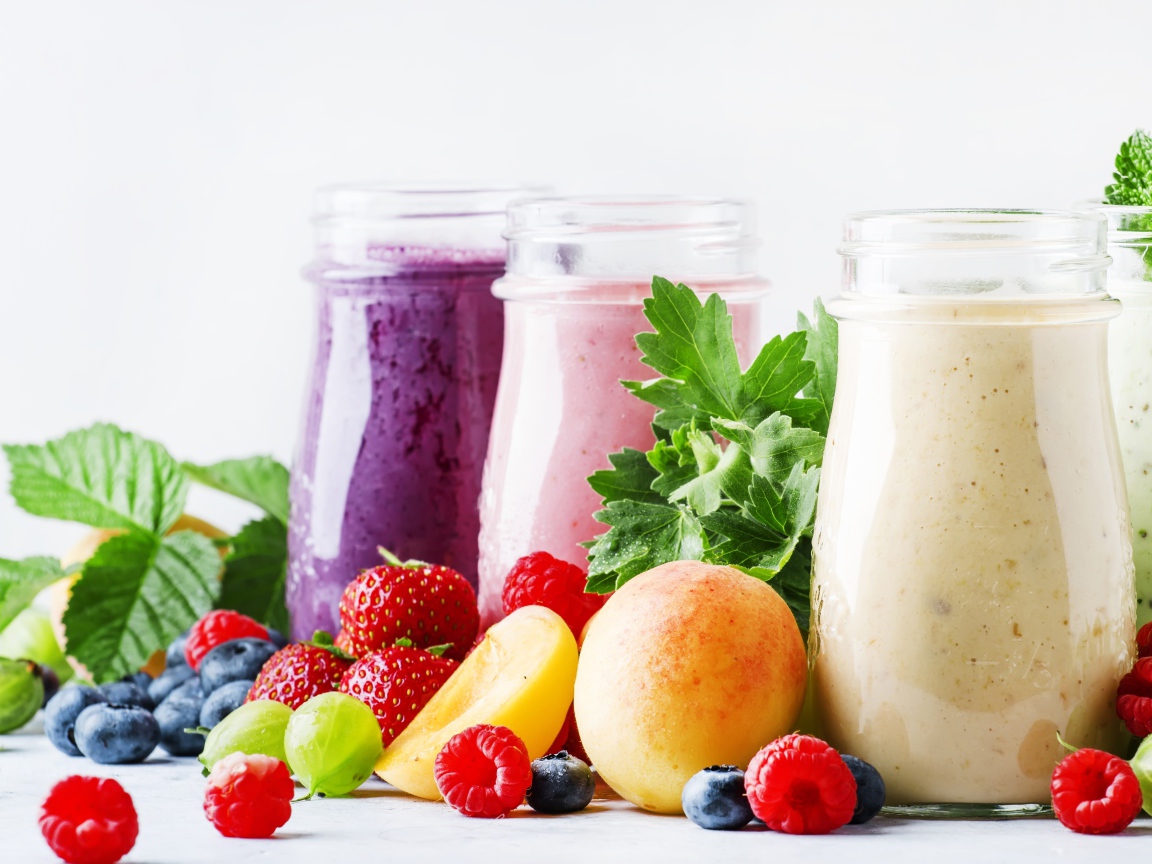 Ягодные смузи в бутылочках на столе с ягодами