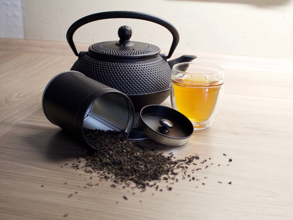Черный чай на столе с чайником и чашкой