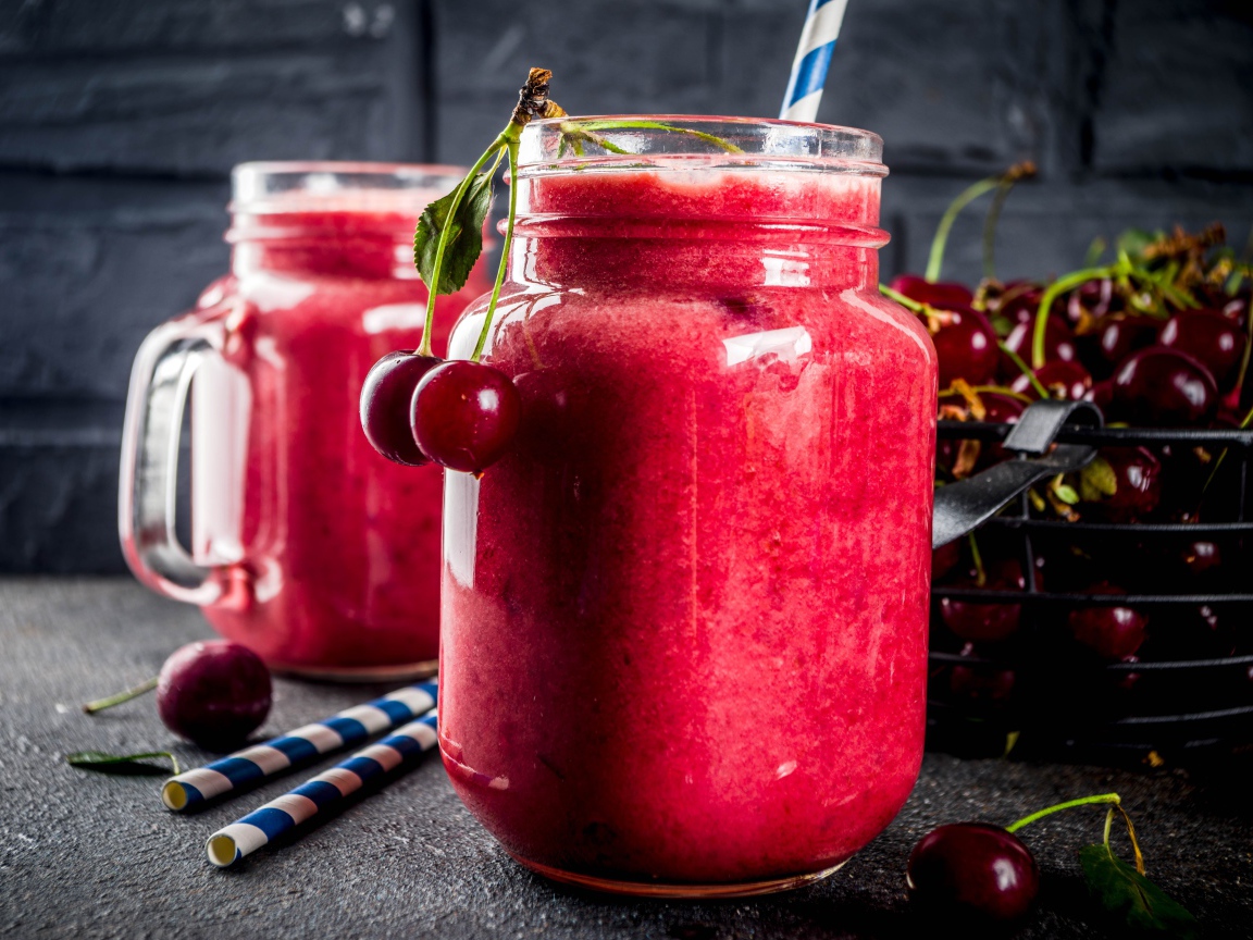 Вишневое смузи в стеклянной банке на столе с ягодами