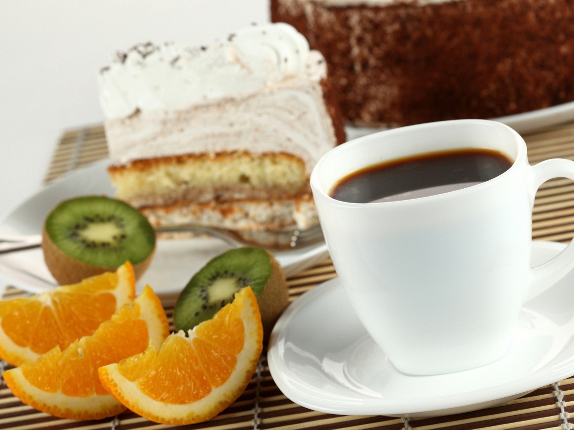 Кофе с куском торта и кусочками апельсина и киви на столе
