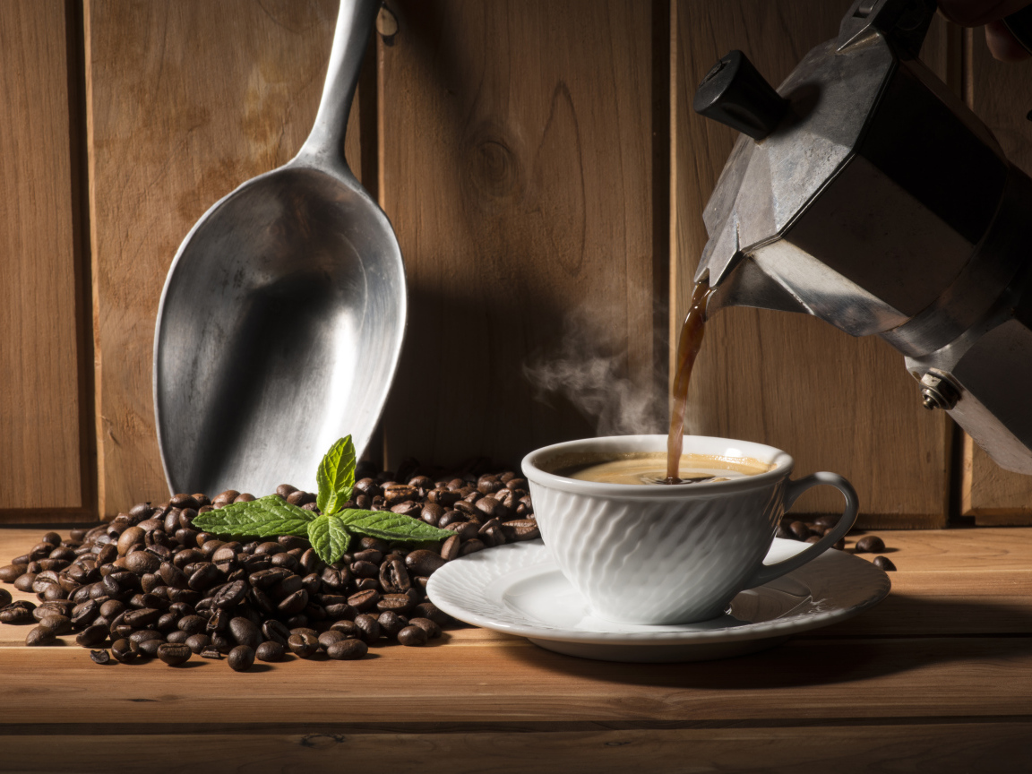 Горячий кофе наливают в чашку на столе с кофейными зернами