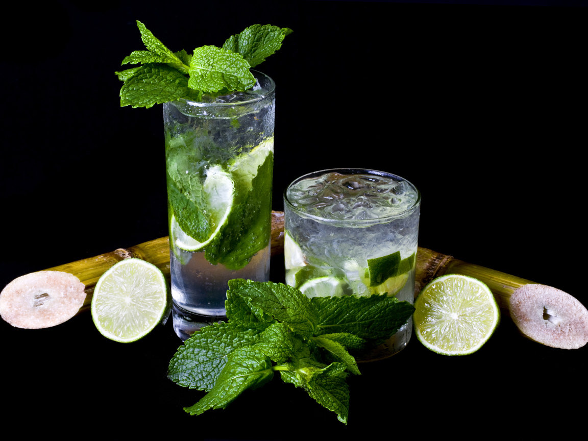 Напиток мохито в стаканах с лаймом и листьями мяты на черном фоне