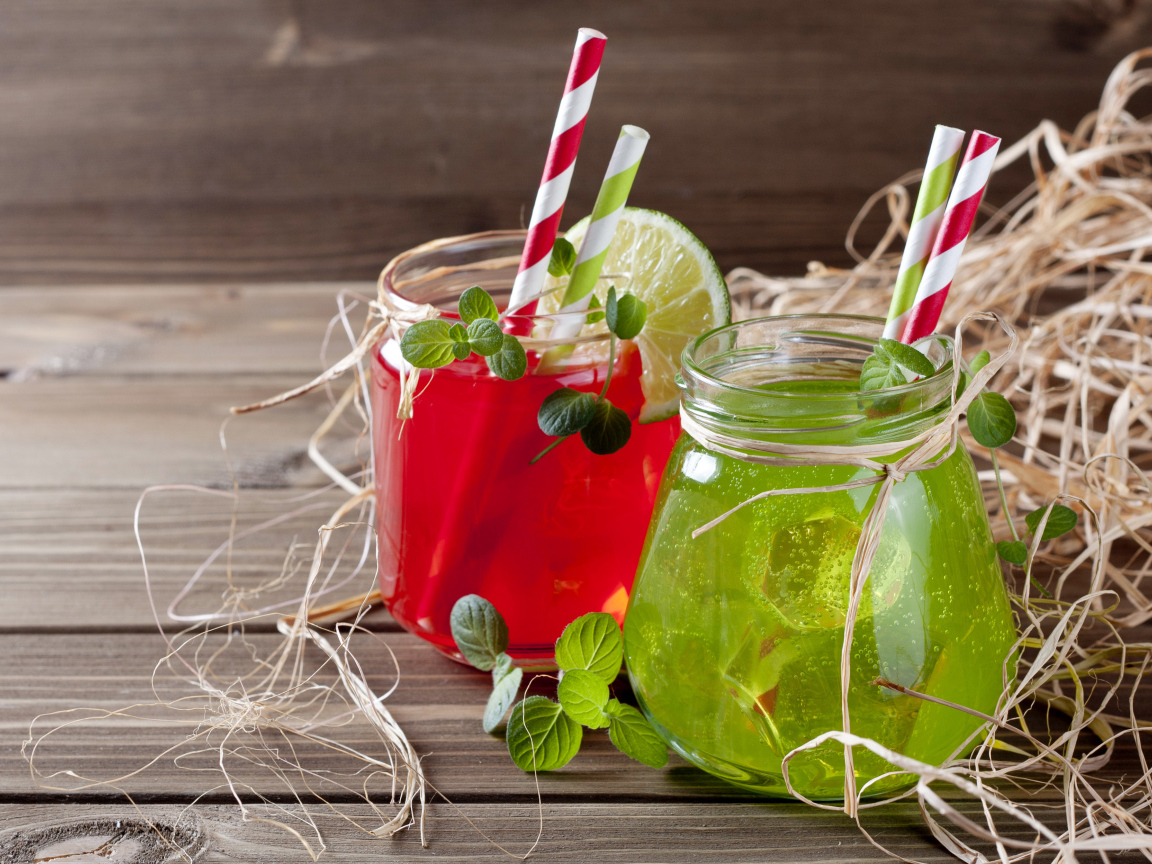 Две банки с коктейлями на деревянном столе с соломой