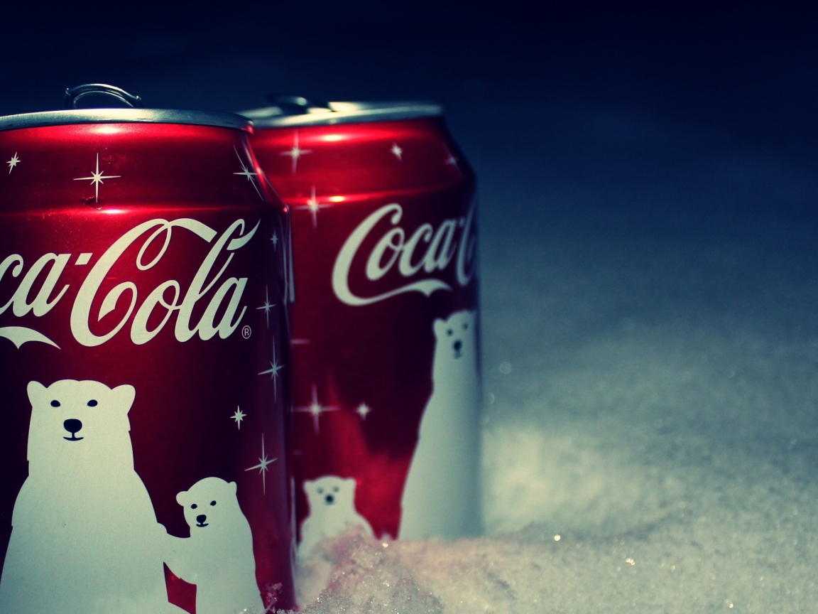 Две красные банки напитка Кока Кола стоят на снегу