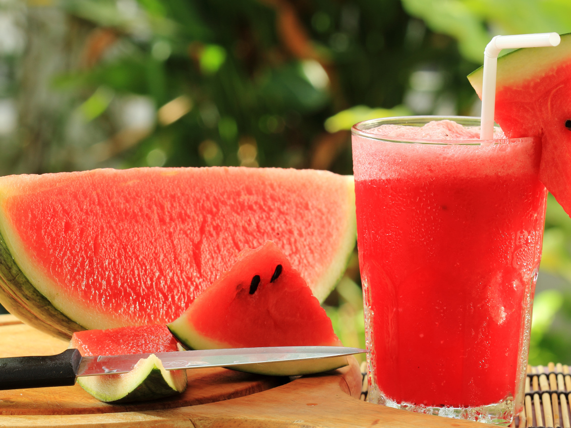 Арбузный напиток в стакане на столе с куском арбуза
