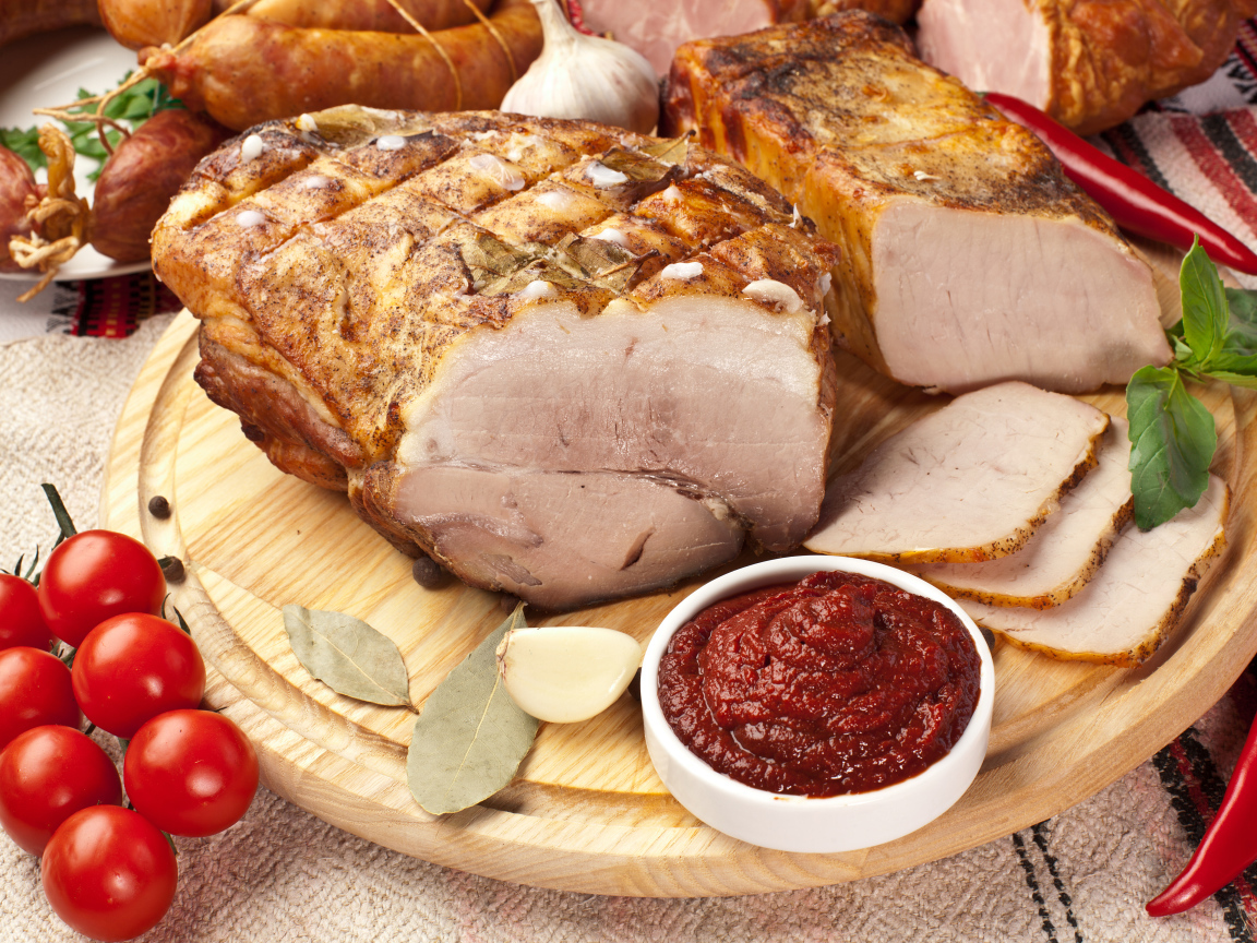 Аппетитная ветчина на столе с соусом и помидорами