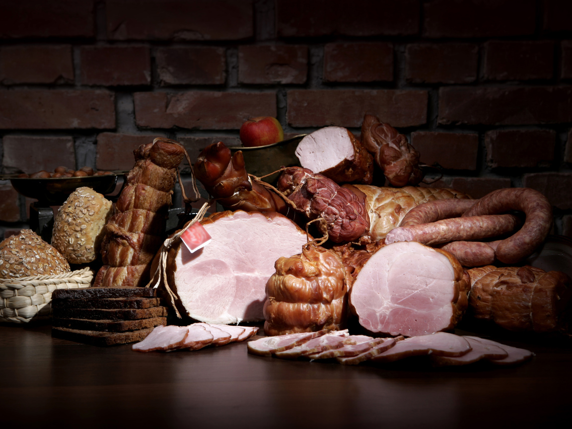 Аппетитные мясные продукты на фоне кирпичной стены 
