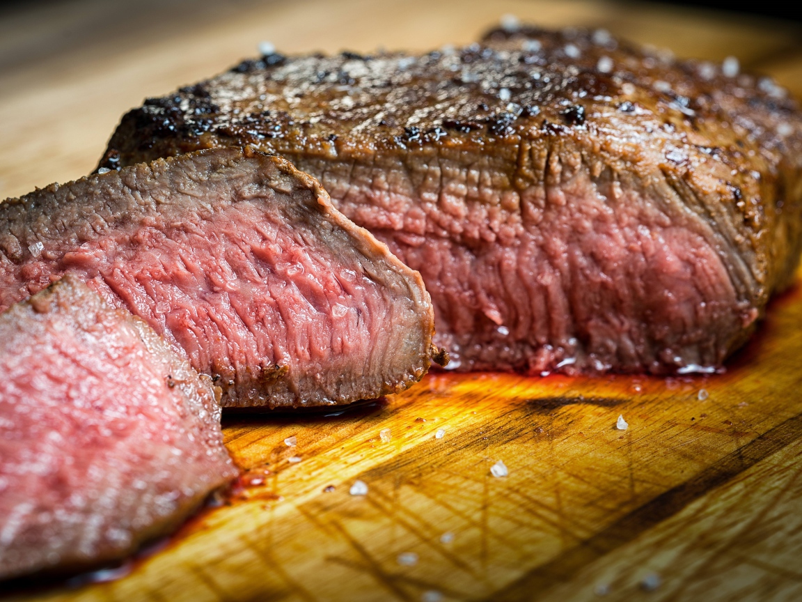 Аппетитный нарезанный кусок мяса на разделочной доске