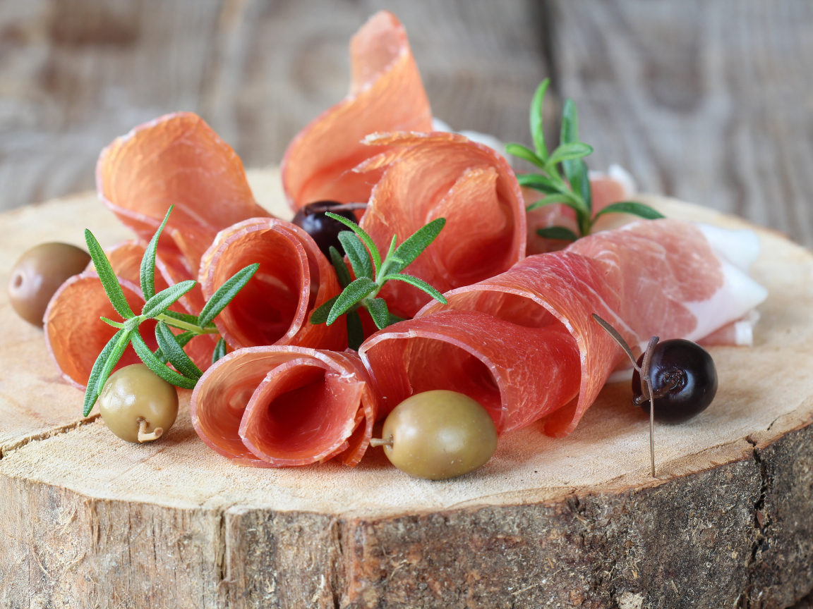 Прошутто  с оливками на деревянном столе 