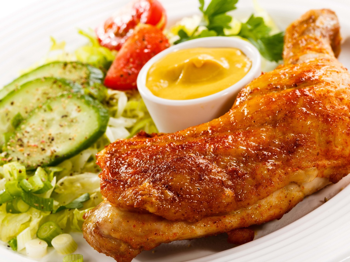 Жареная куриная ножка с овощами и соусом на тарелке