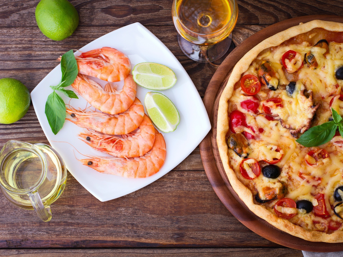 Аппетитная пицца на столе с креветками и кусочками лайма 