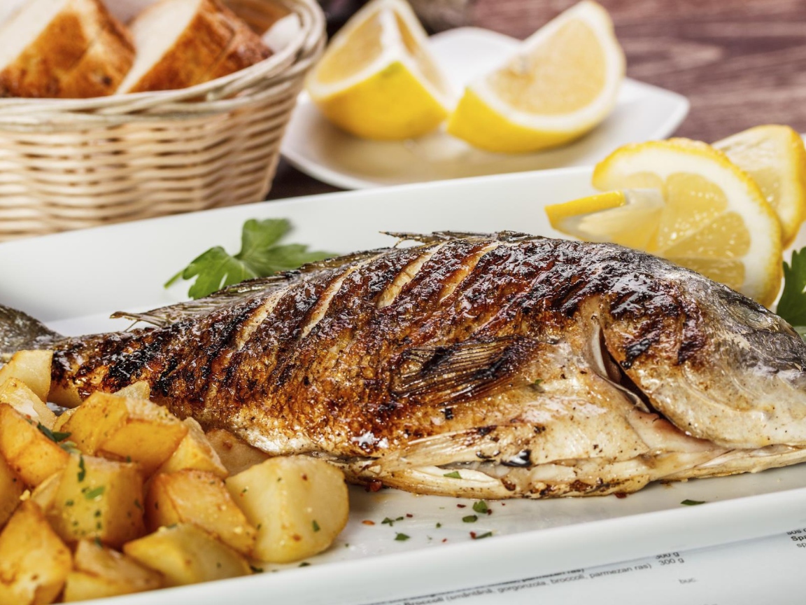 Запеченная рыба на тарелке с картофелем и лимоном 