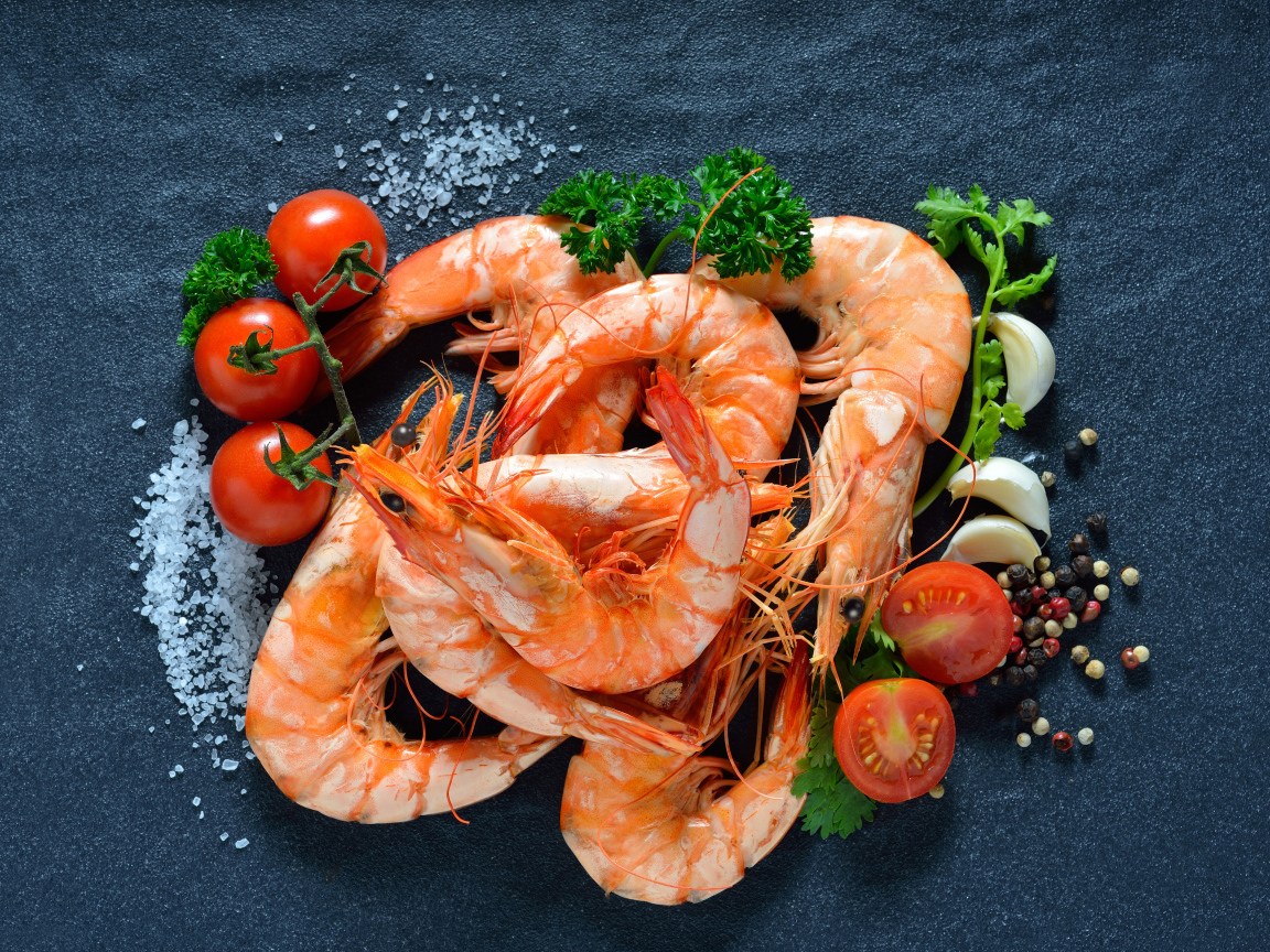 Вареные креветки на столе со специями и  помидорами 