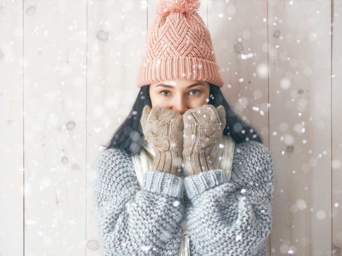 Молодая девушка с теплом свитере с шапкой на голове и перчатках