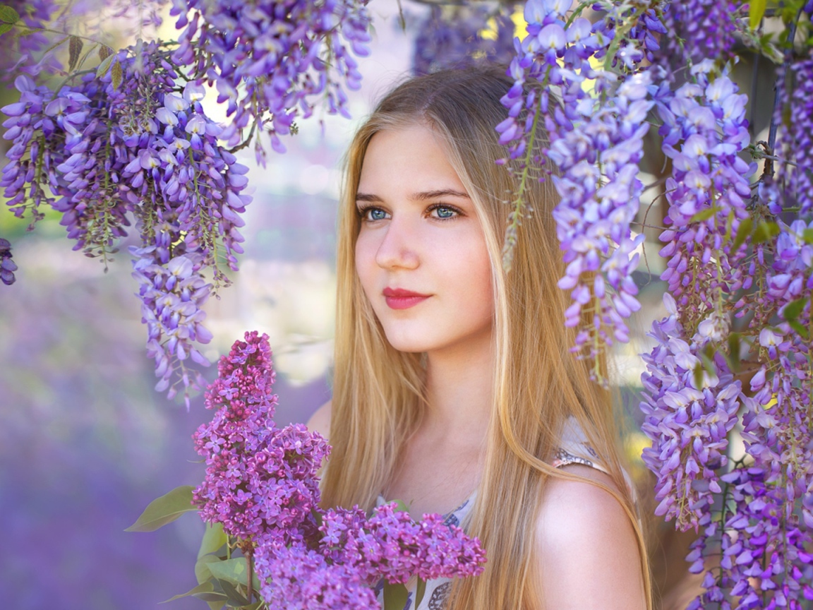 Красивая блондинка с букетом сирени на фоне цветов глицинии