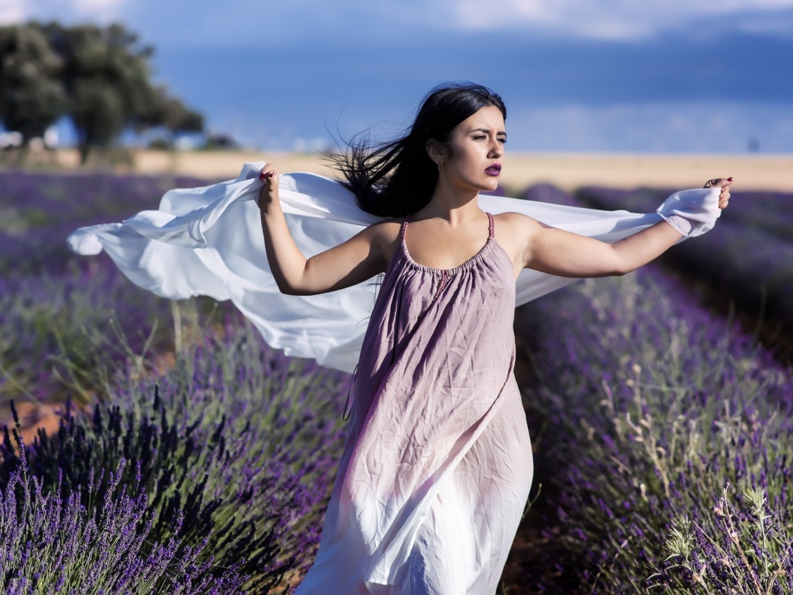 Красивая брюнетка в сарафане гуляет по лавандовому полю
