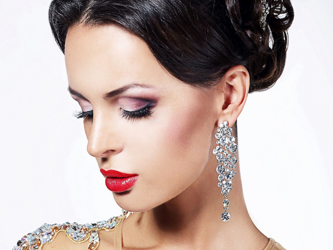 Красивая брюнетка в дорогих украшениях на белом фоне