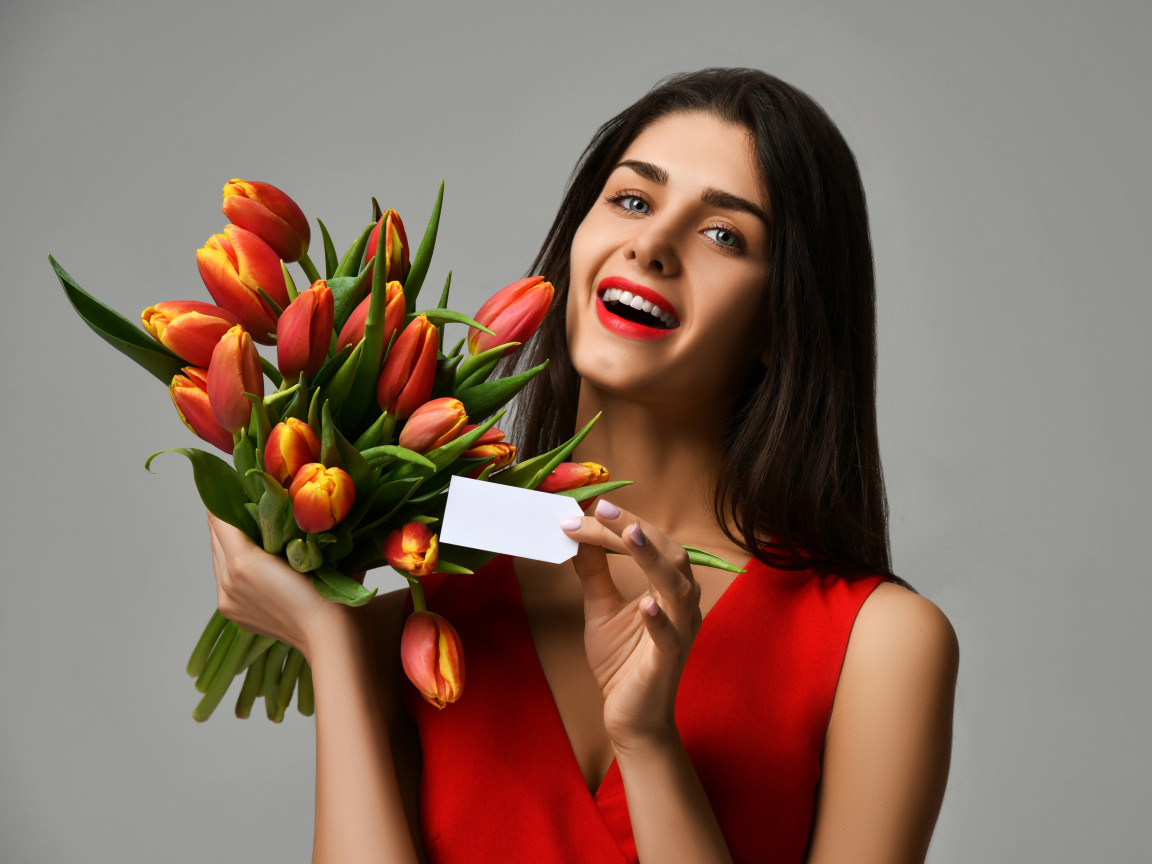 Красивая брюнетка с букетом тюльпанов на сером фоне