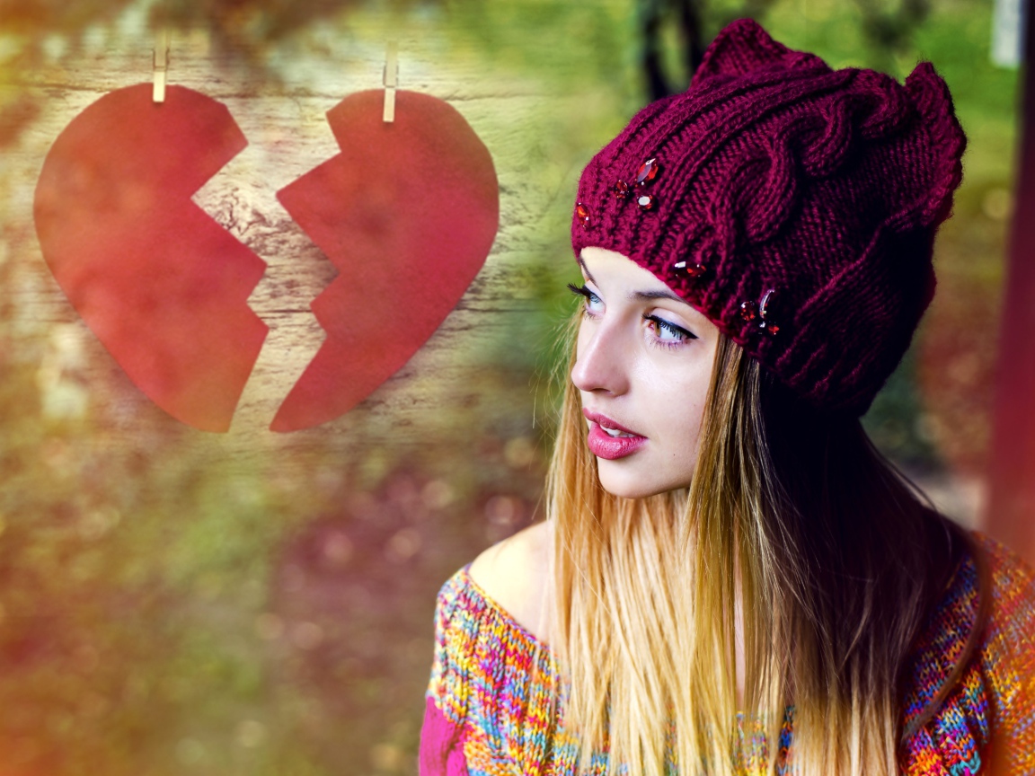 Красивая девушка в вязаной шапке на фоне разбитого сердца