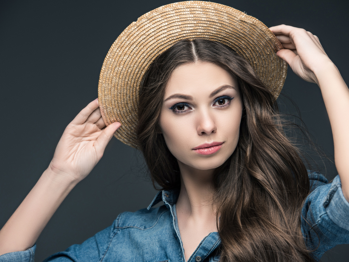 Красивая девушка в соломенной шляпе на сером фоне