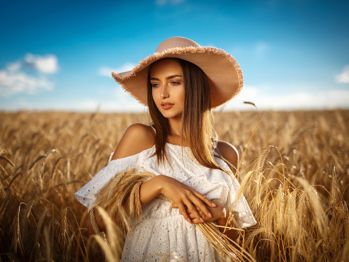 Красивая девушка в белом платье с колосьями пшеницы