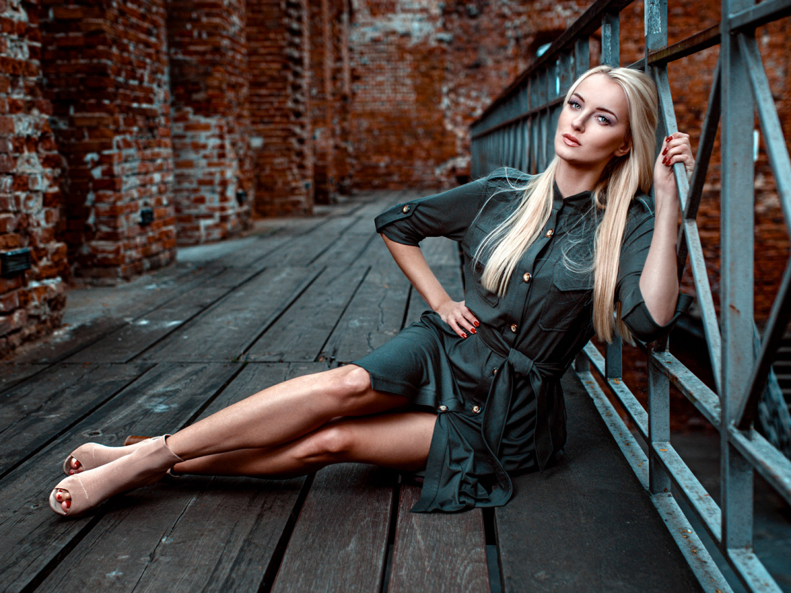 Красивая девушка сидит на деревянном полу