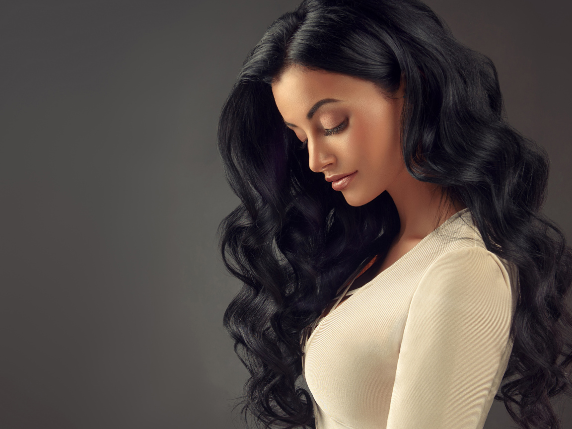 Красивая длинноволосая брюнетка на сером фоне