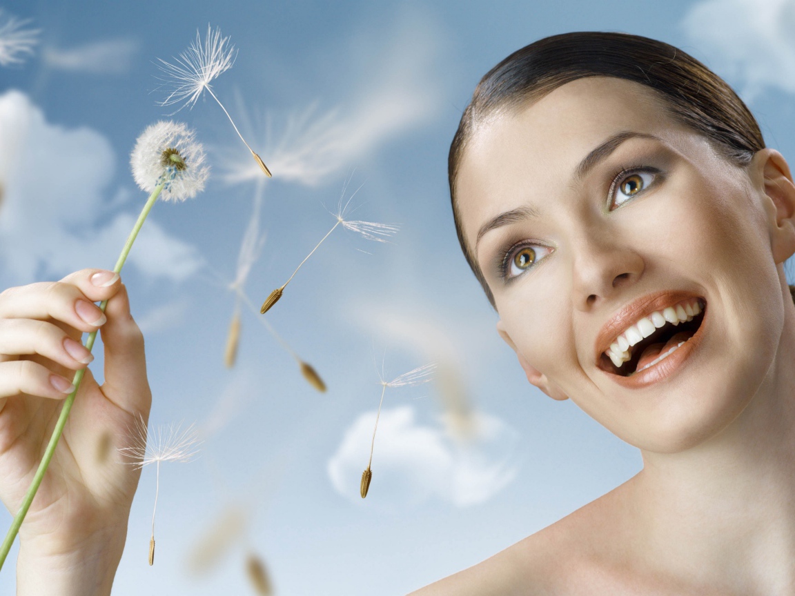 Счастливая девушка с одуванчиком в руке 