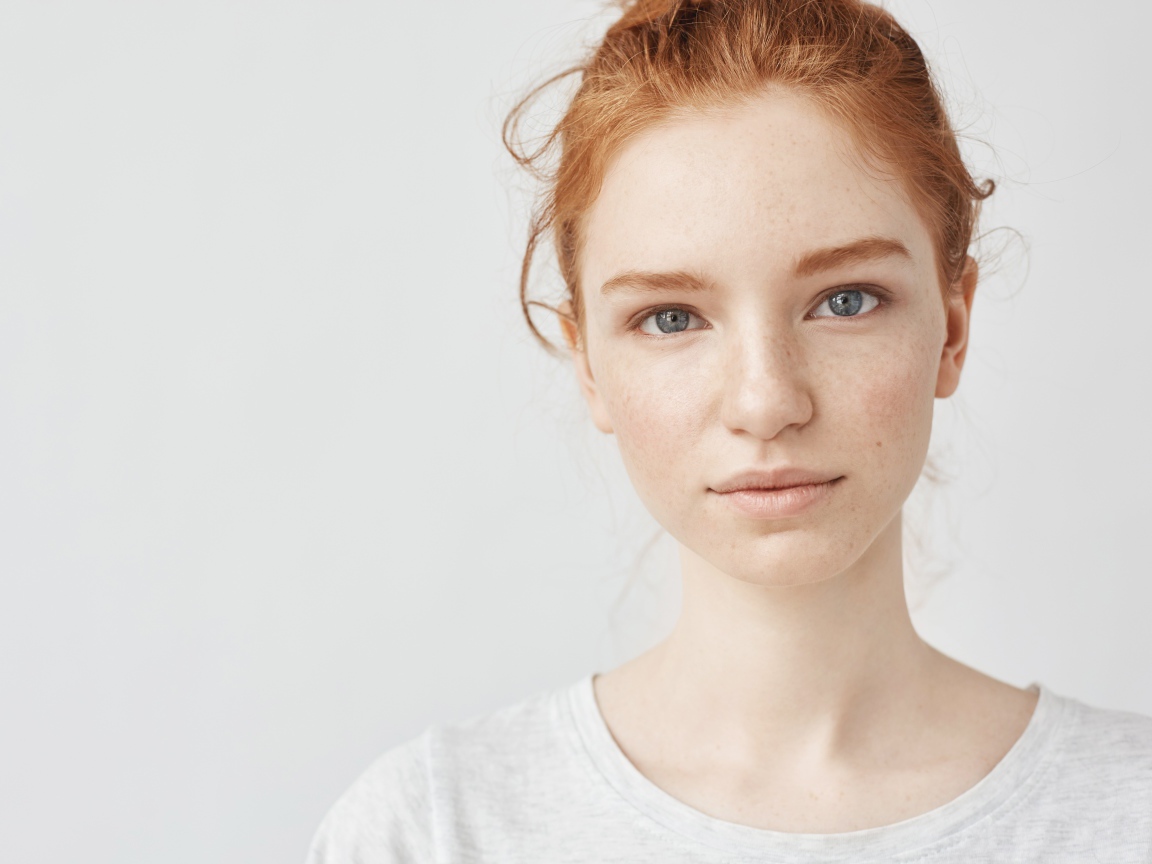 Рыжеволосая девушка на сером фоне