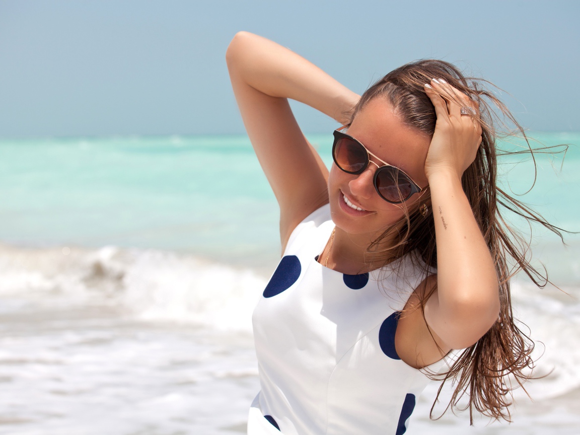 Молодая шатенка в солнечных очках у моря