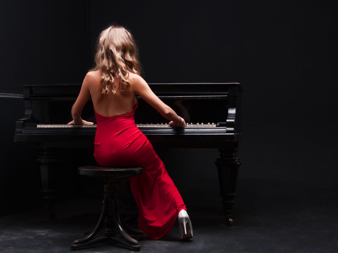 Молодая девушка в красном платье играет на пианино