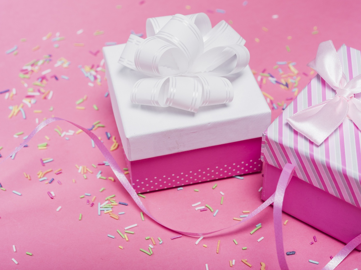 Две подарочные коробки с бантами на розовом фоне