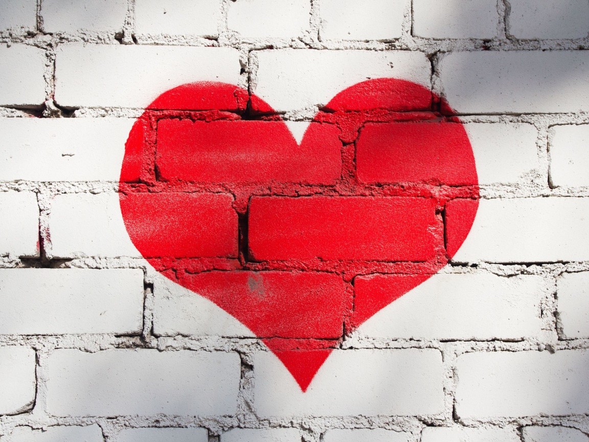 Большое красное сердце нарисовано на кирпичной стене
