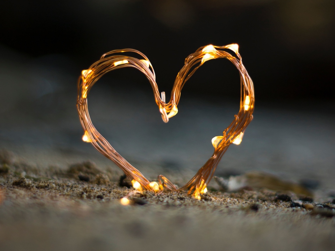 Сердце из гирлянды на песке