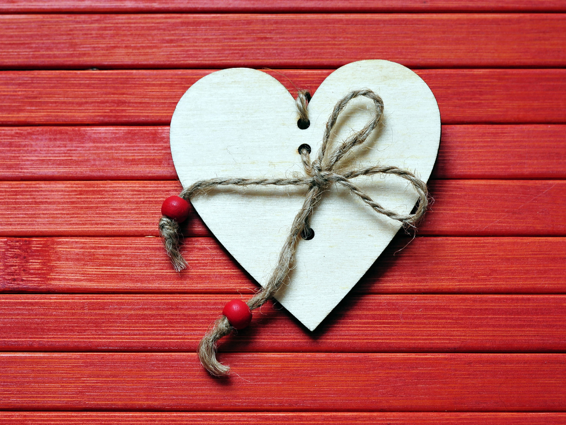 Сердце с веревкой на красном деревянном фоне
