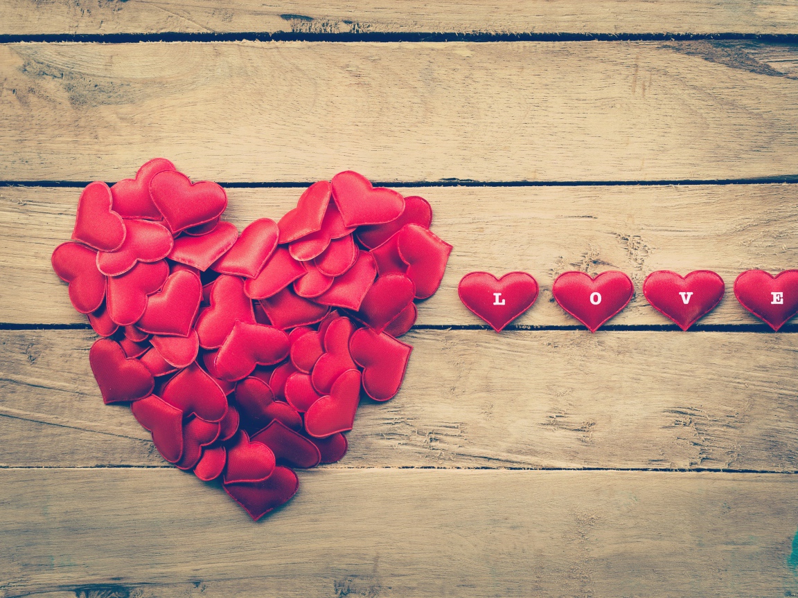 Маленькие красные сердечки на деревянной поверхности 
