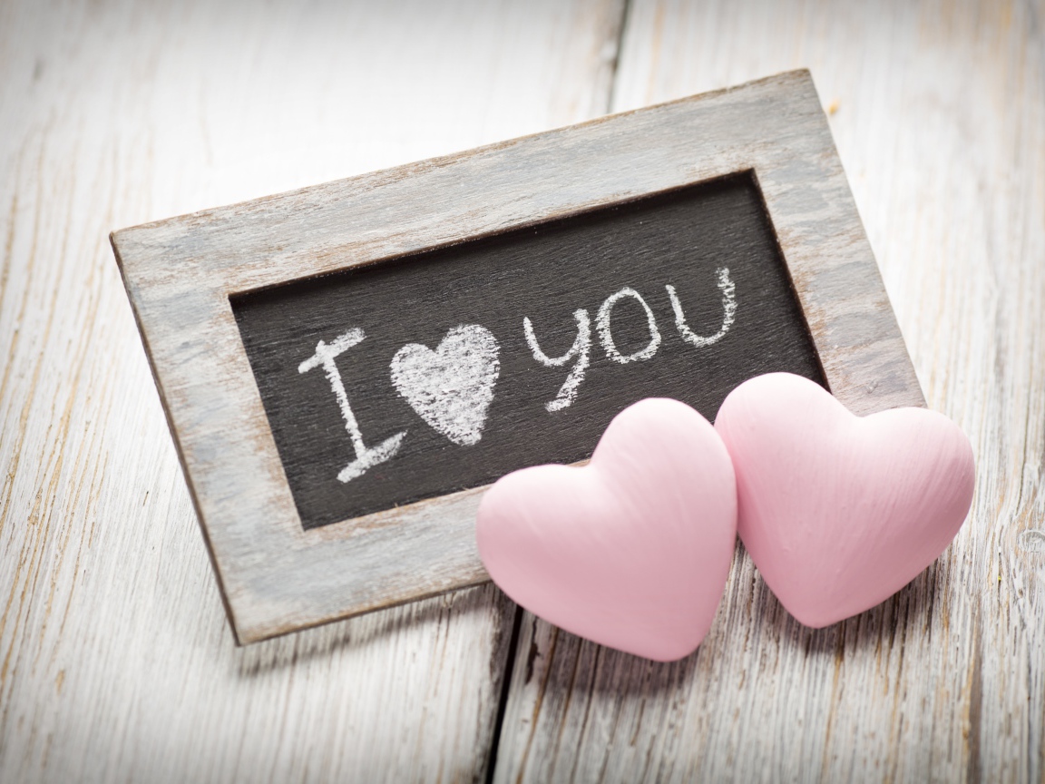 Два розовых сердца на столе с деревянной рамкой