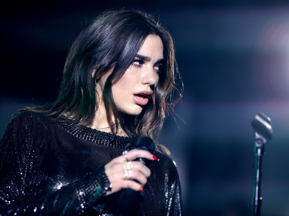 Британская певица Дуа Липа с микрофоном в руках