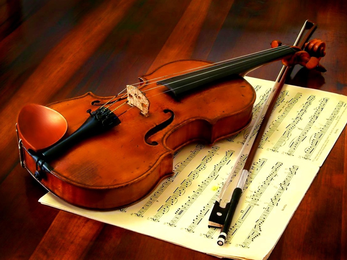 Скрипка со смычком лежат на нотной тетради