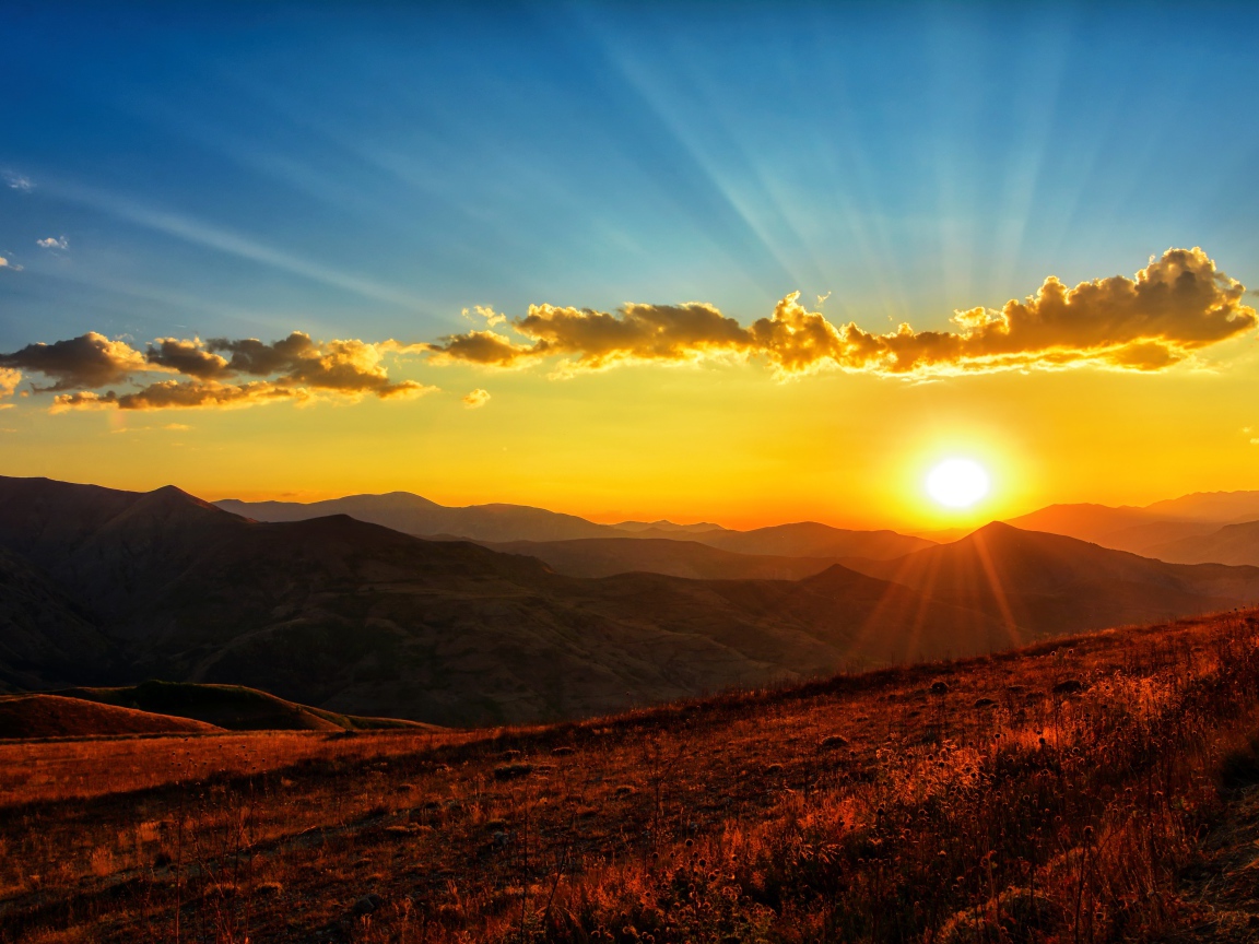 Красивый рассвет в небе над зелеными холмами