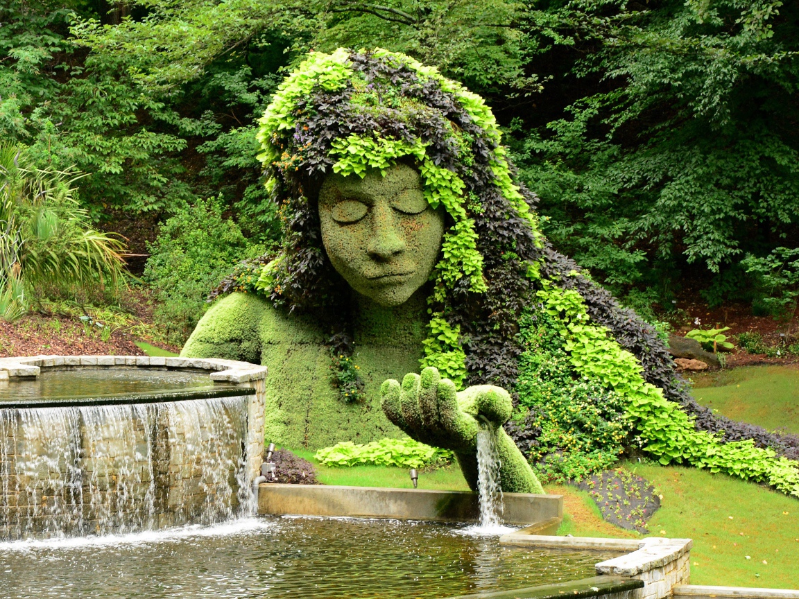 Красивый водопад в парке со скульптурой 