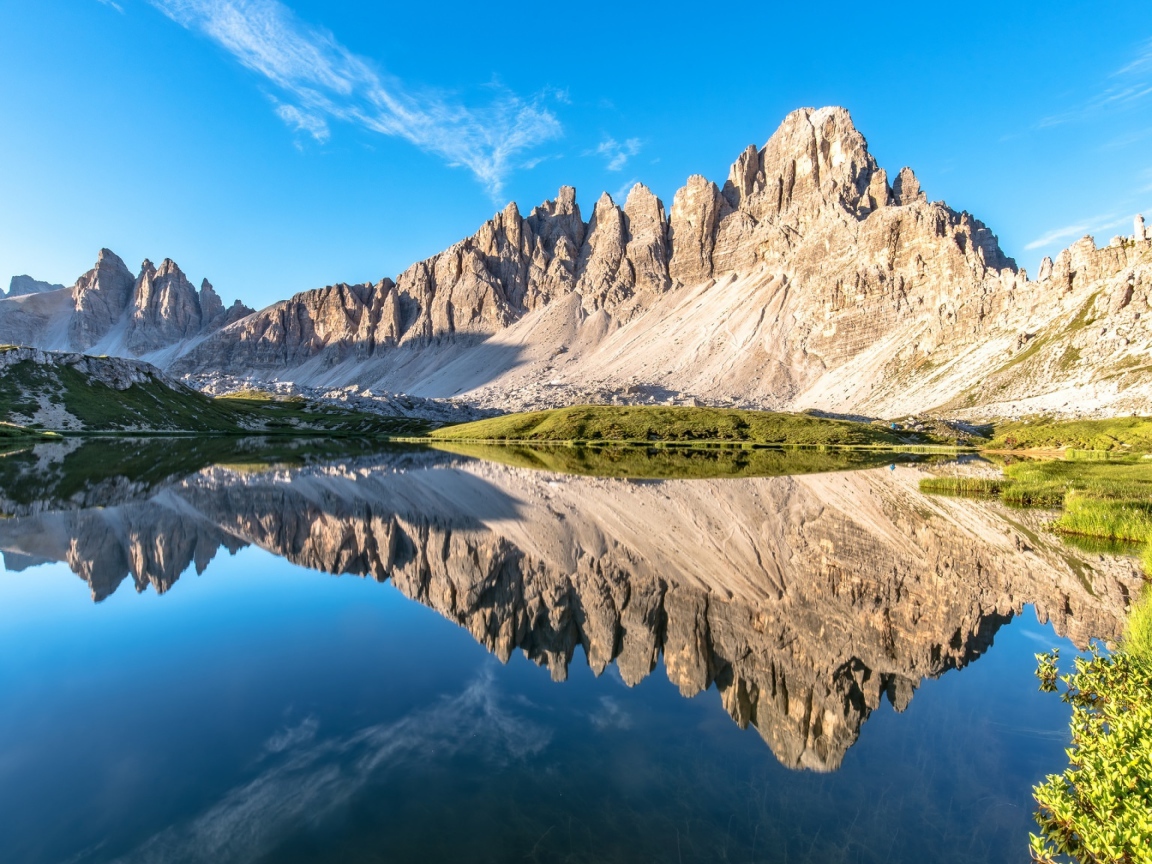 Горы и голубое небо отражаются в чистой воде 