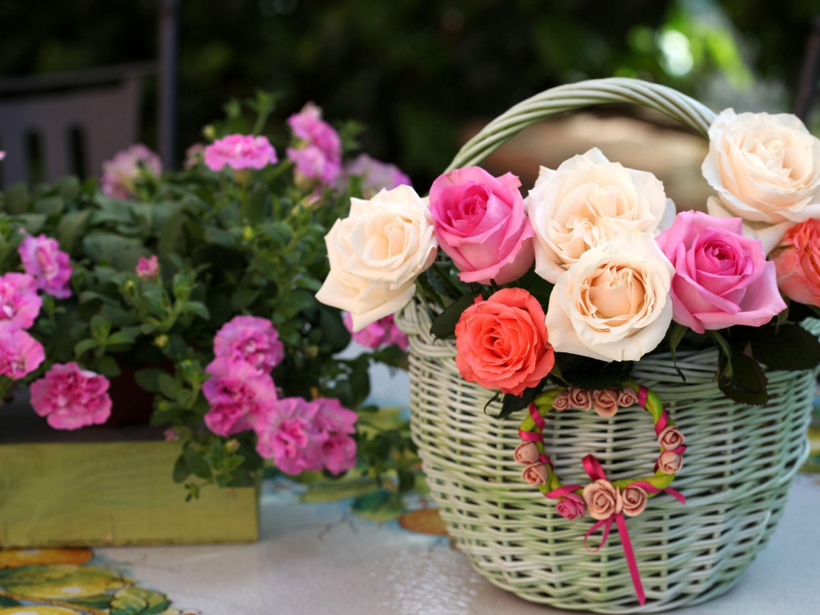 Букет нежных роз в корзине на столе с цветами