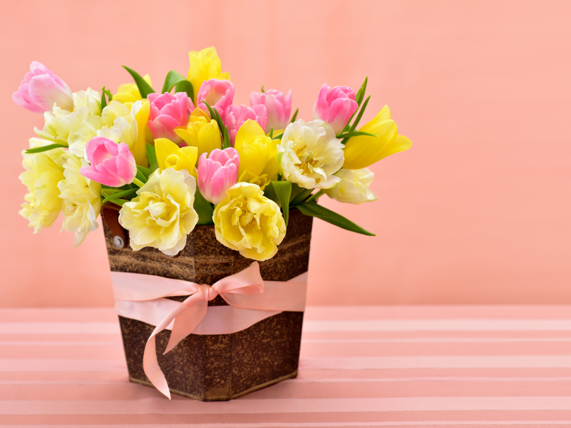 Букет красивых разноцветных тюльпанов в вазе на розовом фоне
