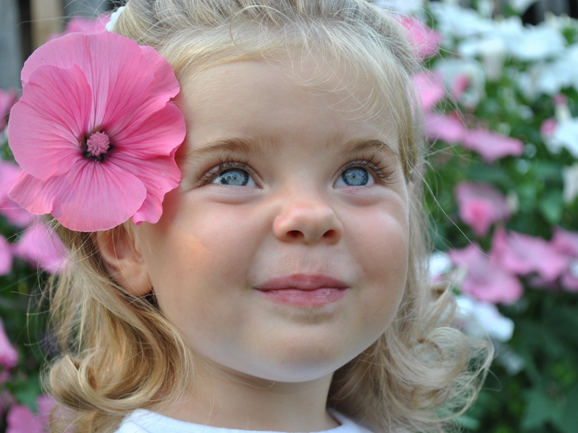 Милая маленькая девочка блондинка с цветком в волосах