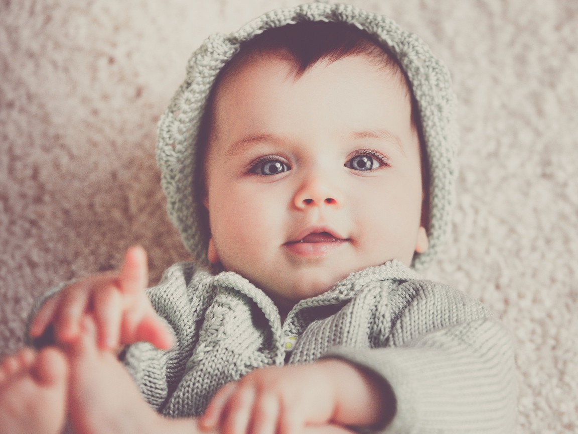 Маленький милый голубоглазый малыш в вязаном костюме